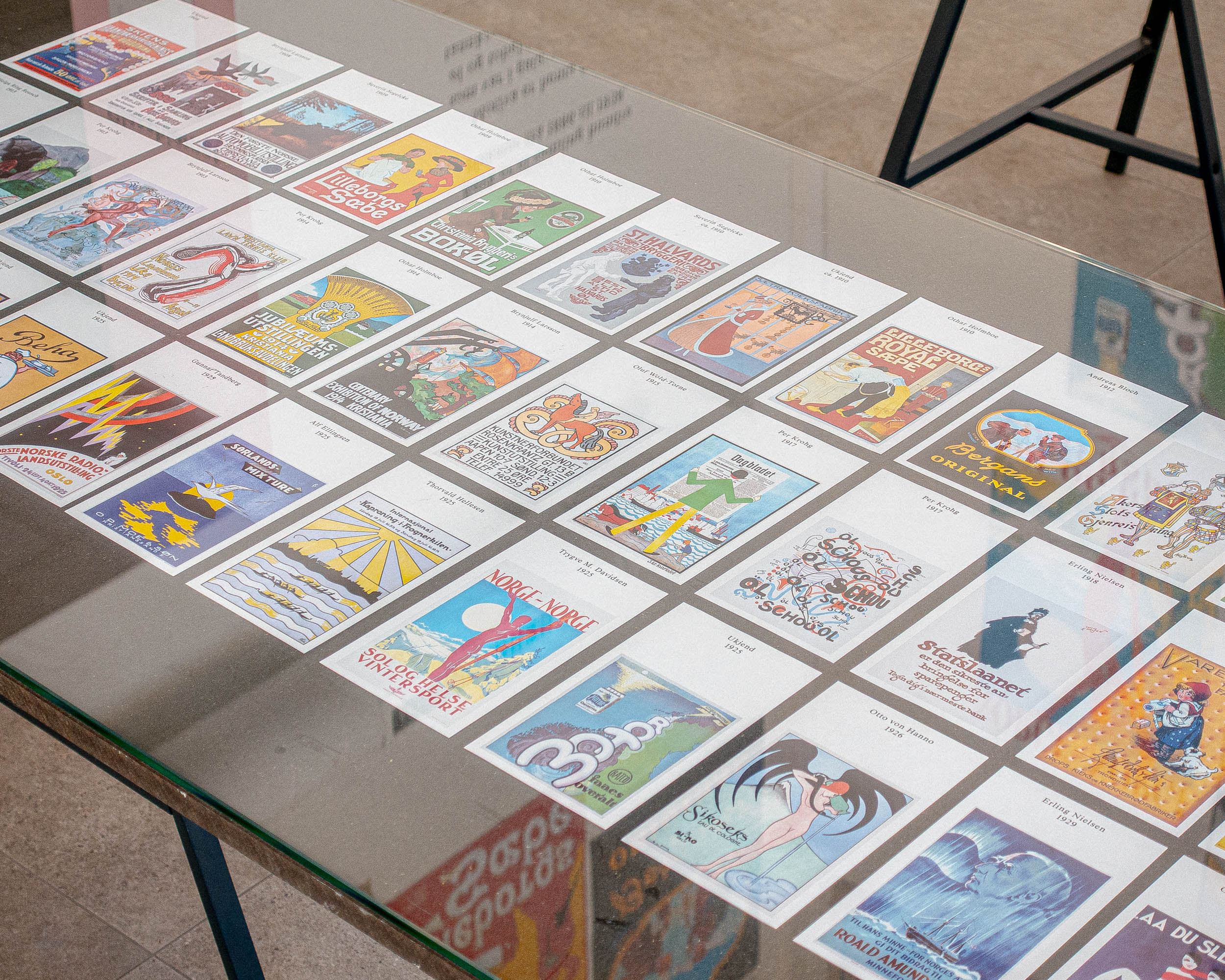 Table display with reproduced posters in the exhibition Røyk